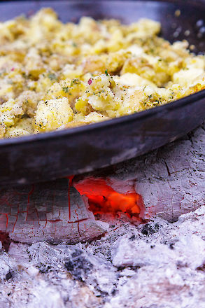 Kasey Mills of Toro Bravo roasts potatoes, olives and capers over an open fire to serve with grilled flank steak at a Growing Gardens Chef in My Garden fundraiser. | © Matt Giraud Photography