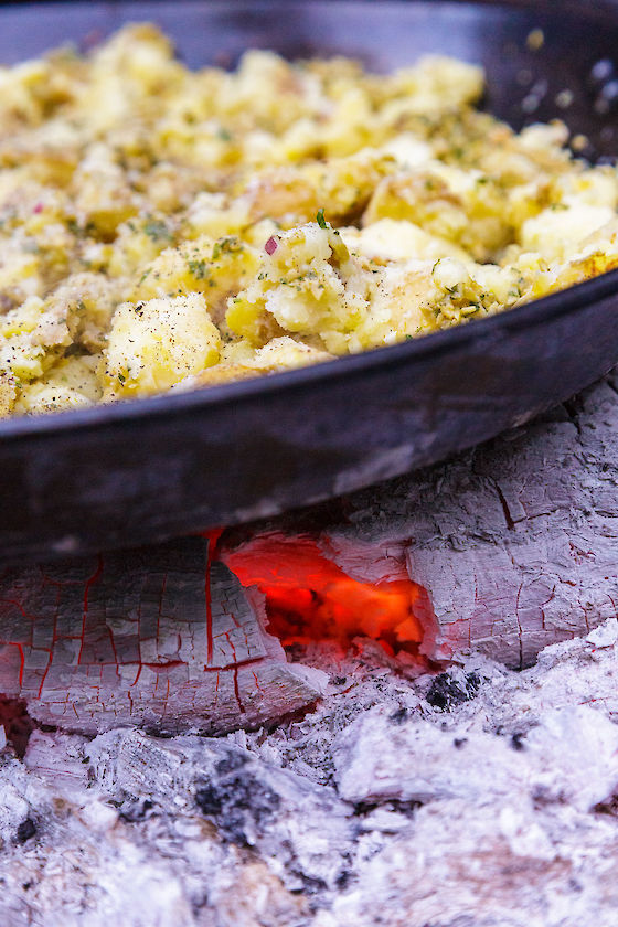 Kasey Mills of Toro Bravo roasts potatoes, olives and capers over an open fire to serve with grilled flank steak at a Growing Gardens Chef in My Garden fundraiser. | © Matt Giraud Photography